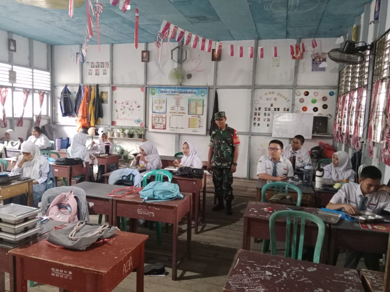 Babinsa Serda Ronald Manalu  menjaga distribusi MBG di SMAN 1 Tembilahan Hulu